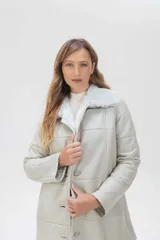 Abrigo midi de cuero con interior y cuello de piel sintética, cierre frontal con botones y bolsillos laterales.