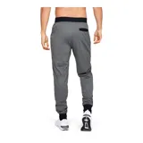 Pantalón deportivo tipo jogger para hombre, color gris jaspeado, con cintura elástica negra y cordón de ajuste. Presenta puños ajustados en los tobillos y un bolsillo lateral con cierre. Logo de Under Armour bordado en la pierna izquierda.