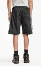 Bermuda deportiva color negro con paneles laterales grises. Presenta cintura elástica con cordón de ajuste estampado, bolsillos laterales y un bolsillo cargo con solapa en el muslo derecho.