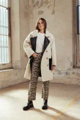 Cazadora larga de estilo doble faz, confeccionada en cuero sintético negro con interior de corderito sintético color crema. Presenta un diseño de corte recto, cierre frontal con botones, solapas amplias y bolsillos laterales.