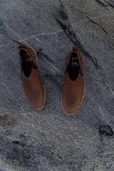 Zapatos tipo chelsea de cuero color marrón, con paneles elásticos laterales y suela plana de goma.