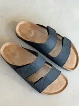 Sandalias negras con dos tiras anchas con costuras en forma de X, plantilla de corcho y suela de goma.