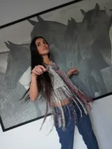 Top tejido artesanal de silueta suelta, con breteles anchos y escote halter. Diseño calado con flecos largos multicolores que aportan movimiento y textura.