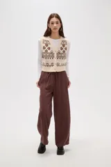 Chaleco tejido de punto con diseño jacquard de corazones y motivos geométricos en tonos verde y rosa. Presenta escote en V, cierre frontal con botones y terminaciones acanaladas en cuello, sisas y ruedo.