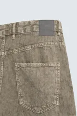 Pantalón de corte baggy fit confeccionado en tejido de algodón con textura y efecto lavado. Presenta diseño de cinco bolsillos, cierre frontal con cremallera y botón.