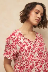 Blusa blanca con finas rayas verticales negras, de manga corta con volados y escote en V con pequeños botones y detalle de volado en el borde.