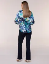 Blusa de gasa estampada de la marca Zac & Rachel, con diseño floral en tonos azul, celeste y verde sobre base blanca. Presenta escote en V con abertura y botones frontales, y mangas largas de largo regulable con presilla.