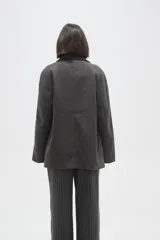 Tapado de paño color gris, con cuello camisero, cierre frontal de botones y bolsillos laterales con solapa.