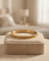 Pulsera tipo esclava rígida de acero con baño de oro, con diseño de banda central texturizada y bordes lisos.