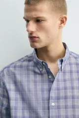 Camisa de corte relajado confeccionada en tejido de algodón, con estampado de cuadros en tonos azules. Presenta cuello abotonado, manga larga con puños abotonados y cierre frontal con botones.