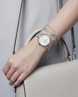 Reloj analógico de mujer con caja redonda plateada, esfera minimalista con índices de puntos y malla de acero tipo milanesa. Diseño elegante y versátil.