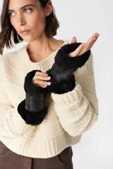 Mitones de cuero negro con interior y bordes de piel sintética tipo corderito. Presentan una chapita metálica decorativa con el logo de la marca.