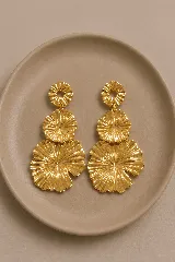 Aros colgantes de diseño floral con tres niveles de piezas circulares texturizadas con relieve radial, acabado en tono dorado brillante.