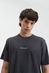 Remera de manga corta color gris oscuro, con estampado frontal de la palabra "Unlimited" en blanco y un pequeño detalle de etiqueta en la manga izquierda.