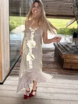 Vestido midi lila con acabado brillante y tirantes finos regulables, diseño con aplicaciones de cuero dorado en el centro y bajo asimétrico con volados.