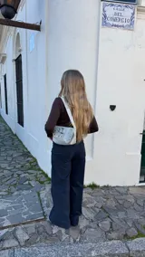 Pantalón de denim oscuro con corte recto y tiro medio. Presenta bolsillos traseros, cierre lateral invisible y tiras ajustables en la cintura.