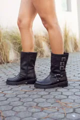 Bota de cuero negra, de caña media, con hebillas decorativas y cierre lateral.