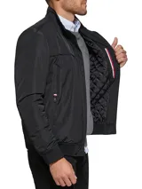 Campera bomber Tommy Hilfiger negra de poliéster, con cuello alto, cierre frontal con cremallera, dos bolsillos laterales con cremallera, puños elásticos y logo bordado en el pecho.