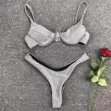 Conjunto de bikini plateado brillante, con corpiño de triángulo con detalle metálico en el centro y bombacha tipo tanga con forro negro.