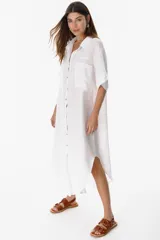 Camisola larga blanca de lino con botones de nácar y bolsillos delanteros.