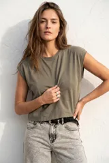 Remera de algodón color verde oliva, con cuello redondo y mangas cortas con hombreras sutiles. Presenta un corte recto y largo a la cintura.