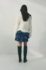 Pollera mini de denim de algodón rígido, con diseño de triple capa de volados escalonados.