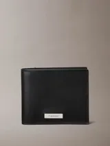 Billetera plegable Calvin Klein confeccionada en cuero liso, con diseño minimalista y placa metálica con logo grabado en la parte frontal.