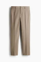Pantalón sastrero de corte ajustado, confeccionado en tejido suave de color beige. Presenta pliegues frontales, cierre con botón, bolsillos laterales y bolsillos traseros ribeteados con botón.