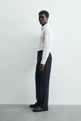 Camisa blanca de manga larga con cuello italiano y puños abotonados, confeccionada en tejido de algodón.