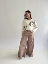 Sweater de punto color marrón chocolate con diseño floral bordado en cordón color crudo. Presenta cuello redondo, mangas largas y puños acanalados.