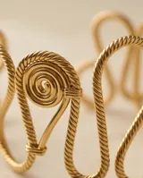 Brazalete rígido de acero con baño de oro, con diseño de ondas entrelazadas y acabado texturizado.