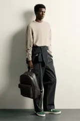 Mochila marrón oscuro con acabado abatanado, compartimento principal con cierre, bolsillo frontal con solapa y asa de mano.