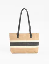 Bolso tipo canasto de playa de paja color beige con franjas horizontales negras y blancas. Tiene doble asa de hombro de cuero sintético negro.