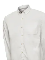 Camisa de manga larga RKF modelo Galiton, confeccionada en popelina de algodón orgánico. Presenta cuello clásico, cierre frontal con botones de madera, un bolsillo en el pecho con logo bordado y mangas ajustables. Incluye protección solar UPF 20+.