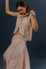 Pollera larga de lino color gris topo, de diseño amplio con volumen, movimiento y bolsillos delanteros. Cuenta con elástico en la cintura y detalles de pinzas y sobretelas en los laterales.
