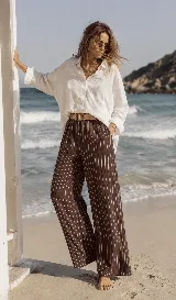 Pantalón de lino azul marino con finas rayas verticales blancas, de corte amplio y talle alto. Incluye bolsillos funcionales y una cintura elástica con cinturón de rafia desmontable.