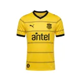Camiseta de fútbol Puma del Club Atlético Peñarol, modelo Away 2026. Diseño en color amarillo vibrante con finas líneas horizontales negras, cuello en V y puños en contraste. Incluye logo de Puma, escudo del club bordado, sponsor Antel en el frente y sello histórico del CURCC en el lateral inferior.