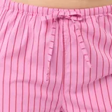 Pantalón de pijama de corte recto y holgado, confeccionado en tela de popelina color rosa con estampado de rayas verticales finas en tono oscuro. Presenta cintura elástica con cordón de ajuste frontal.