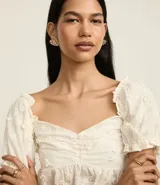 Blusa peplum color blanco, confeccionada en algodón, con escote corazón, mangas abullonadas cortas y bordado floral.