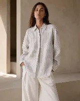 Camisa oversize de lino con diseño de rayas verticales sutiles, cuello camisero clásico, cierre frontal oculto y puños con detalle de tablitas.