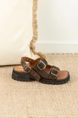 Sandalias de cuero marrón con plataforma de goma negra y hebillas metálicas.