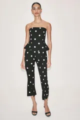 Mono largo de escote recto sin tirantes, con peplum en la cintura, perneras acampanadas y estampado de lunares.