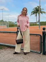 Camisa de textura ligera en color rosado, con cuello clásico, cierre frontal de botones y un bolsillo en el pecho. Presenta mangas largas y un corte holgado.
