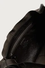 Bolso bandolera de piel color marrón oscuro, con diseño flexible y solapa frontal. Cuenta con asa larga ajustable y compartimento principal con bolsillo interior con cierre.