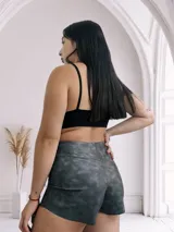 Short pollera gris con efecto gastado, cierre lateral con cremallera, cordón ajustable en la cintura y detalle de tachas plateadas en el frente.