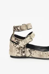 Balerina baja de cuero con grabado de reptil en tonos beige y negro. Cuenta con doble tira de ajuste en los tobillos con hebillas metálicas y remaches de níquel. Suela de goma con plantilla acolchonada y punta cuadrada.