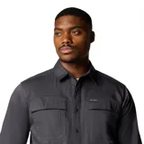 Camisa de manga larga Columbia, color gris oscuro, con cierre frontal de botones a presión, dos bolsillos frontales con solapa y trabilla multiusos.