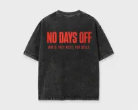 Remera oversize de algodón con lavado a la piedra, color negro con efecto desgastado. Presenta un estampado frontal en color rojo con la frase 'NO DAYS OFF' y el texto 'WHILE THEY REST, YOU BUILD.'