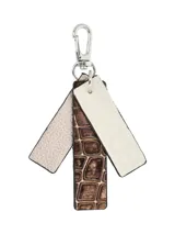 Llavero con mosquetón metálico y tres tiras colgantes de diferentes texturas: una en cuero texturizado color beige, una central con efecto piel de cocodrilo en tono cobre y una tercera en cuero liso color crema con logo grabado.