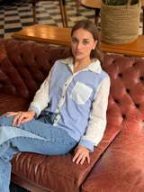 Camisa de corte clásico con diseño combinado, presenta cuerpo a rayas verticales en azul y blanco, con mangas largas y cuello en tela broderie blanca con detalles calados. Incluye bolsillo frontal en broderie y cierre central con botones.
